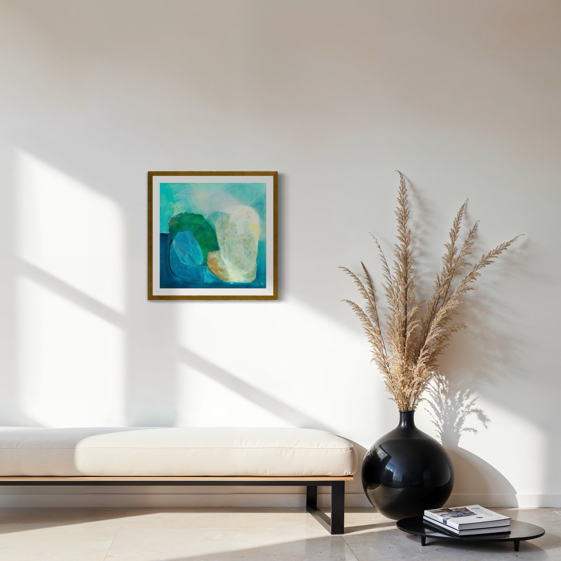 Gems, Abstract Fine Art Print on Paper with a classic frame of sustainable sourced wood painted in gold. This artwork has nature inspired abstract shapes with playful movements in blue, emerald green, white, burnt orange. Hanging on a white wall above a bench with a large black vase on the floor next to it. Ingeborg Andersson Art